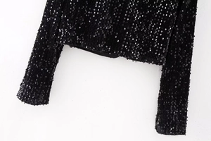 Gros plan des paillettes noires scintillantes sur le haut Y2K à manches longues et coutures