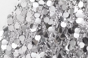 Gros plan détaillé du tissu à paillettes argentées avec reflets métalliques et base en maille