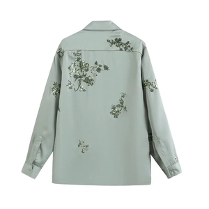 Detail view of light green Y2K shirt featuring dark green sequin floral embroidery on back