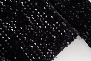 Vue macro de paillettes noires sur haut ajusté montrant les détails et la brillance