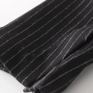 Macro close-up showing the premium black pinstripe fabric and stitching of the blazer