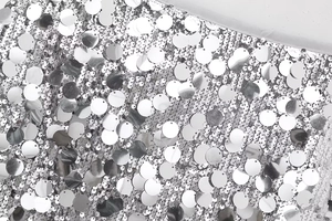 Détail de paillettes argentées brillantes en écailles sur une mini-jupe style Y2K