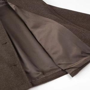 Detail view of smooth satin lining and neat stitching inside a brown wool coat