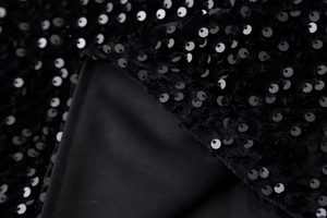 Détail de paillettes noires denses sur haut à manches longues avec doublure douce