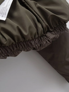 Macro detail of the olive green padded jacket showing elastic cuff and wash care label