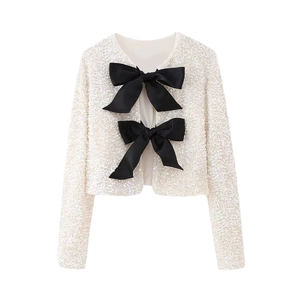 Détail d'un gilet court à paillettes blanches avec de grands nœuds en satin noir chic