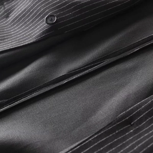Detailed close-up of black pinstripe suit fabric featuring a round button and clean stitching