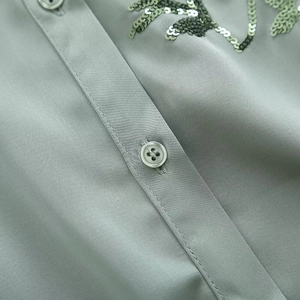 Detail of sage green shirt with sparkling leaf sequin embroidery and matching resin buttons