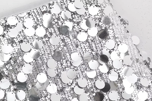 Détail macro de paillettes argentées et tissu résille sur une mini-jupe Y2K