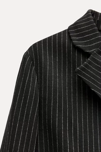 Close-up of the notch lapel and fine pinstripe fabric texture on a structured black blazer