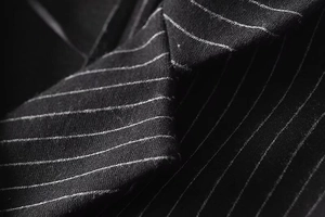 Macro close-up showing the pinstripe fabric texture and lapel detail of the suit jacket