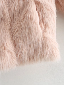 Close-up of soft light pink faux fur texture and stitching on Y2K winter coat