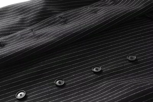 Macro shot of vertical white pinstripes on black suit fabric with four round buttons