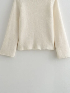 Detailed view of the fine rib-knit texture on a cream-colored slim-fit crewneck sweater