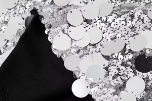 Détail macro de paillettes argentées sur maille blanche avec texture métallique et relief
