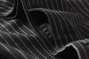 Close-up of premium pinstripe suit fabric showing pocket detail and fine stitching