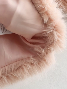 Detail showing plush pink faux fur texture and smooth satin lining with care label