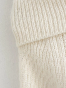 Close-up of white chunky ribbed knit fabric detail showing texture and craftsmanship
