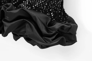 Détail de paillettes noires scintillantes et drapé élégant en satin sur mini robe