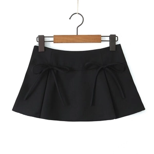 Detail view of black A-line mini skirt featuring decorative bows and pleated design accents