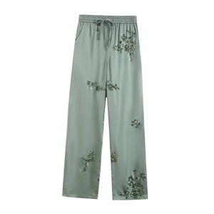 Detail of sage green satin wide-leg pants with intricate sequin floral embroidery
