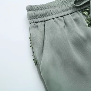 Detail of sage green lounge pants featuring sequin side pockets and drawstring elastic waist