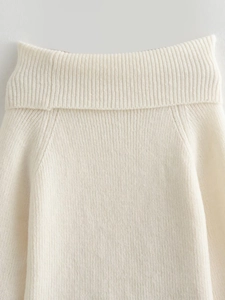 Detailed macro shot showing ivory white ribbed knit texture and roll neck on the sweater
