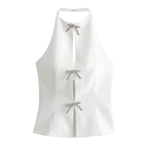 Detailed view of white halter top featuring three sparkling silver bow-shaped fasteners