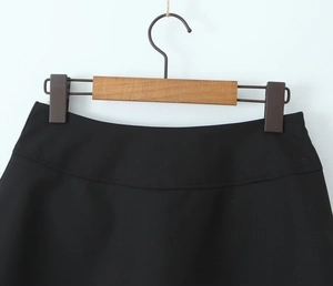 Detailed close-up of a black A-line mini skirt showing wide waistband and neat stitching