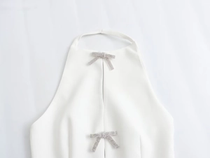 Detail view of white halter top featuring sparkling rhinestone bow accents and split neckline