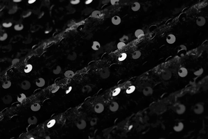 Détail macro du tissu à paillettes noires scintillantes sur une robe en velours chic