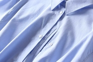 Macro shot of light blue long-sleeved shirt with crisp collar and white buttons