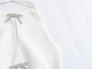 Detailed view of white halter top neckline with two sparkling silver rhinestone bows