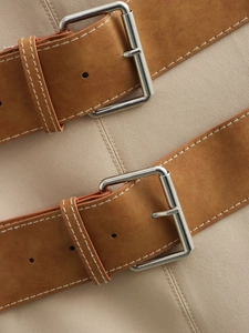 Détail de doubles ceintures en cuir marron avec boucles en métal sur une robe beige clair