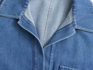 Detalle del cuello de camisa vaquera azul lavada con costuras de contraste marrón