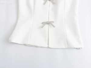 Detail of white slim fit top featuring silver rhinestone bow accents and clean seams