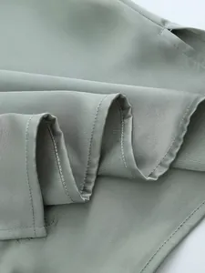 Close-up of sage green sequined shirt fabric showing textured weave and side slit detail