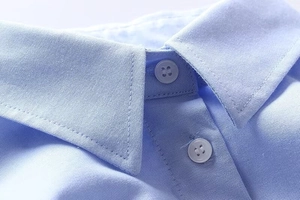 Close-up of light blue shirt collar with neat stitching and tone-on-tone buttons