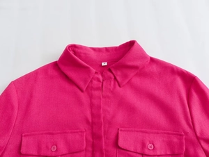 Detail of rose red long sleeve shirt showing fabric texture, pointed collar, and pocket