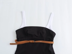 Détail d'une robe bicolore noir et blanc avec ceinture en cuir marron et boucle en métal