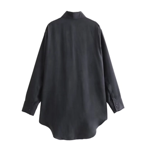 Detail view showing the curved hemline and smooth satin texture of the black long-sleeve shirt