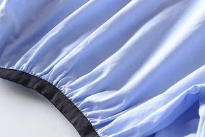 Detail of light blue shirt hem with elastic band and black contrast border trim
