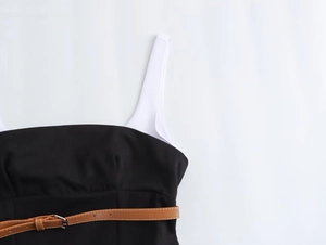 Détail d'une robe bicolore noir et blanc avec une fine ceinture en cuir marron et boucle