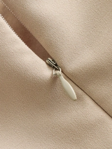 Détail macro d'une fermeture éclair invisible et d'un curseur sur une robe en sergé beige