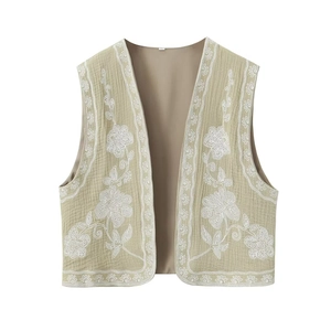 Détail de la broderie florale sur un gilet sans manches vert olive clair en tissu gaufré
