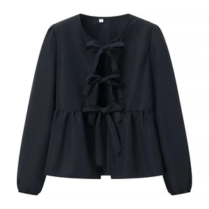 Detail of black peplum blouse with three front bow ties and elastic cuffs on a white background