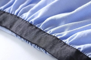 Detail of light blue piqué fabric texture with elastic black hem and neat stitching