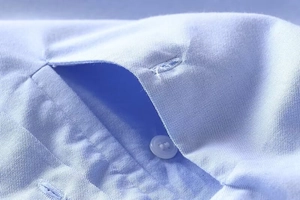 Detailed macro view of the light blue shirt chest pocket and white resin button