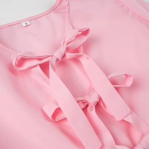 Detail of pink satin long sleeve shirt featuring V-neck and double bow tie accents