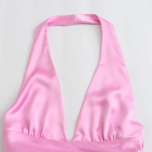 Dettaglio del top a lupetto in raso rosa con scollo a V profondo e design plissettato